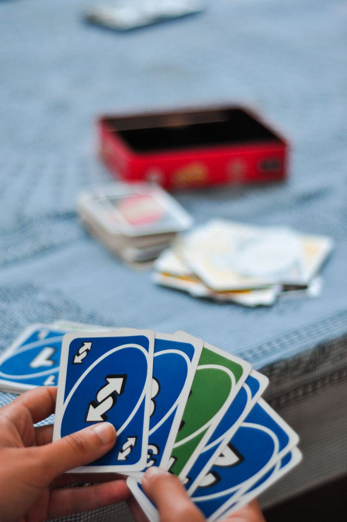 Services Hands holding and playing Uno cards with a blurred background on a table.