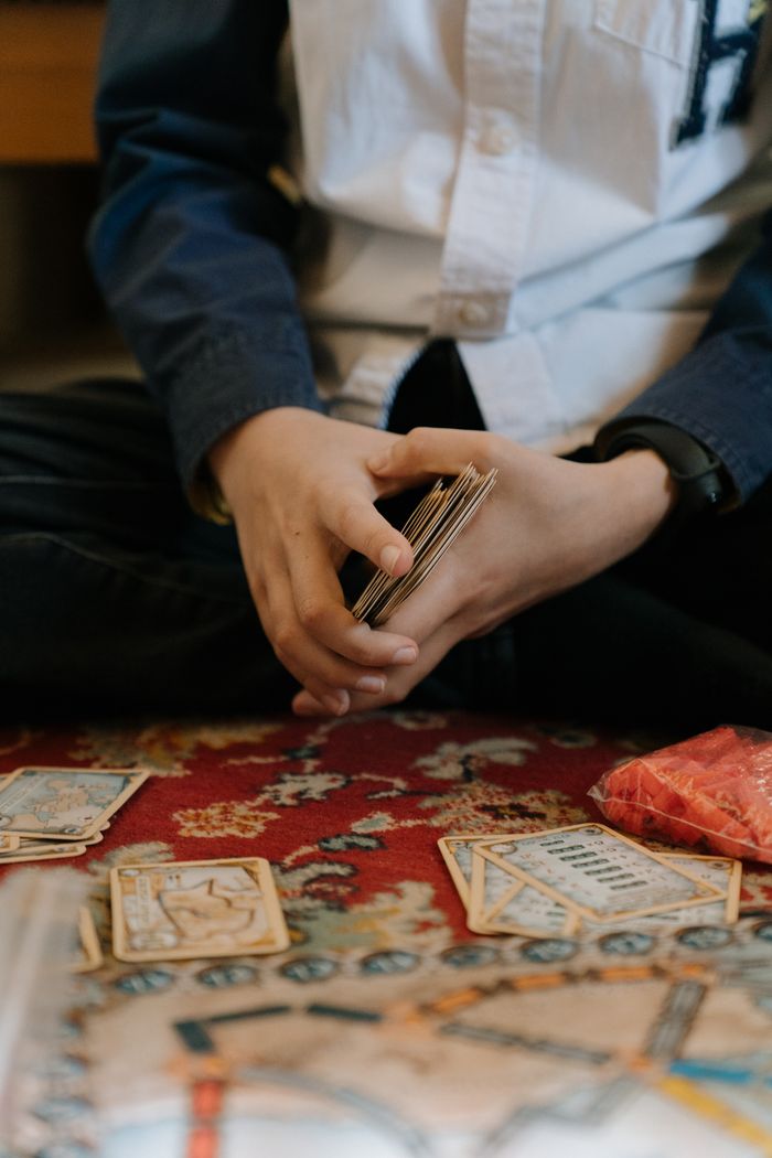 Services A child plays a card game on a patterned carpet, focusing intently indoors.