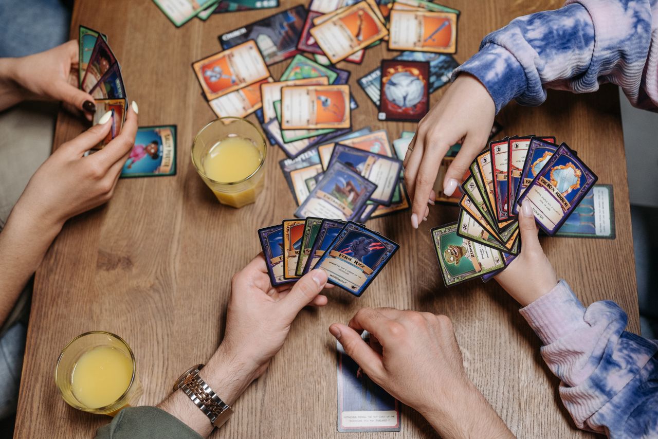 Services Close-up of friends playing a card game at a table, fostering socialization and togetherness.